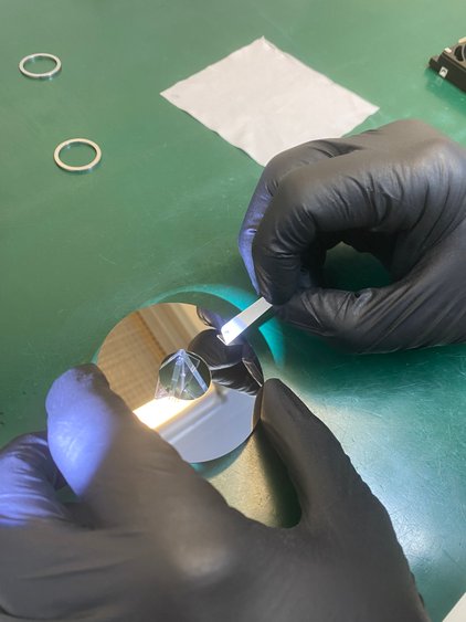 Close-up of gloved hands inspecting hard drive platter in R3 cleanroom