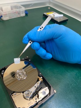 R3 engineer cleaning hard drive platter with precision swab in cleanroom