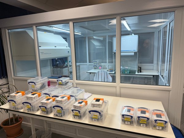 R3 cleanroom viewed through windows with labelled drive cases on intake bench