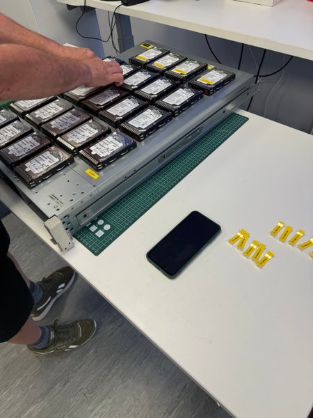 Engineer labelling RAID member drives on a tray at an R3 lab bench