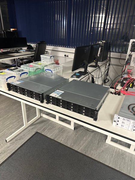 Rack-mount servers and labelled case boxes on an R3 lab workbench prepared for enterprise RAID recovery